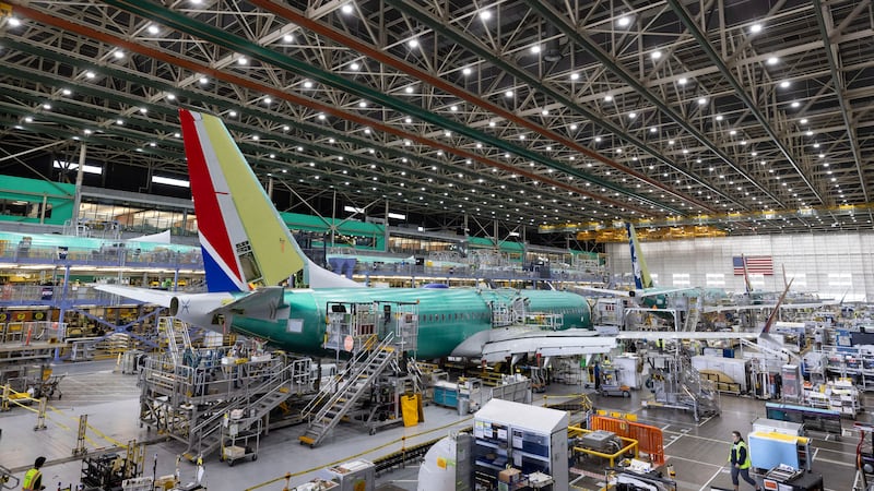 FILE - Boeing employees work on a 737 Max on the final assembly line at Boeing's Renton plant,...