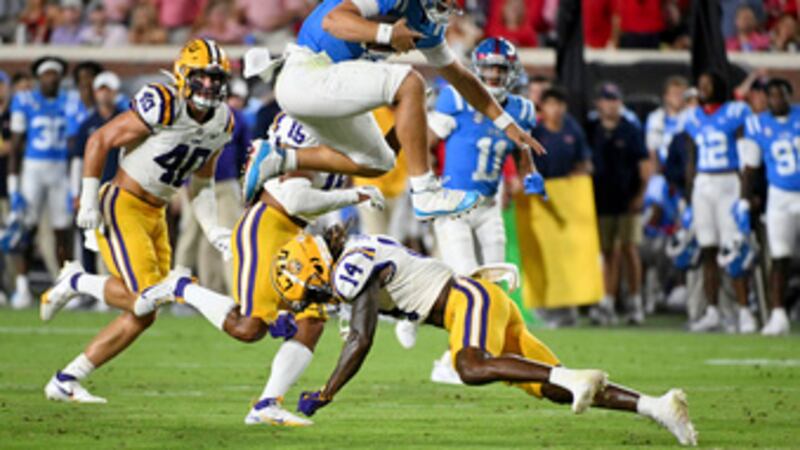 Mississippi quarterback Jaxson Dart, top, hurdles LSU safety Andre' Sam (14) during the second...